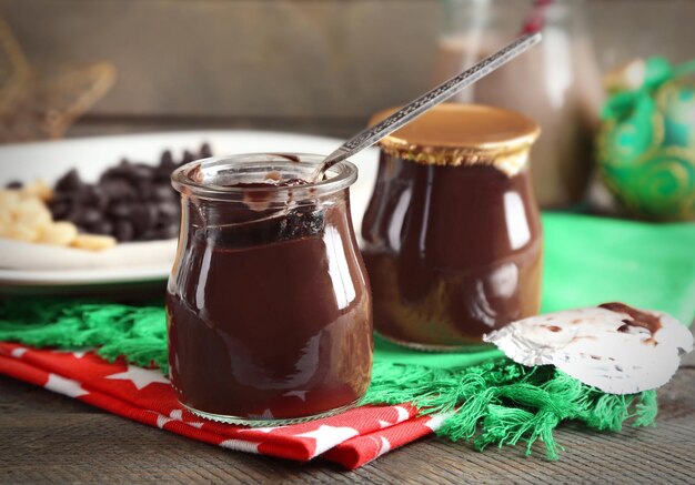 Dessert al cioccolato in vasetti di vetro e cocktail al latte al cioccolato su sfondo di legno