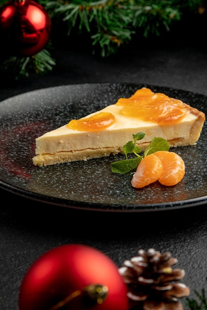 Dessert al mandarino guarnito con spicchi di mandarino e menta, servito su un piatto nero. piatto su sfondo nero di natale