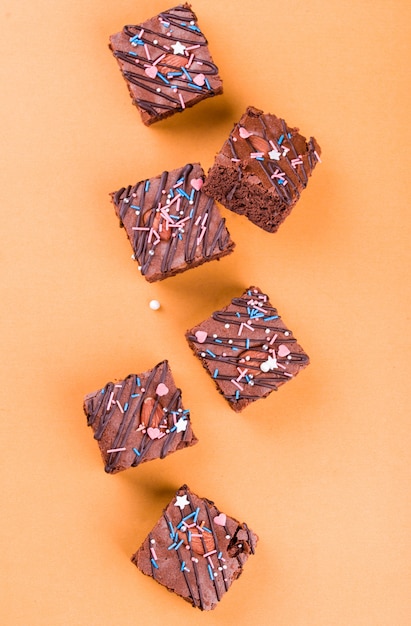 Dessert brownie al cioccolato con mandorle, glassa al cioccolato su una superficie arancione