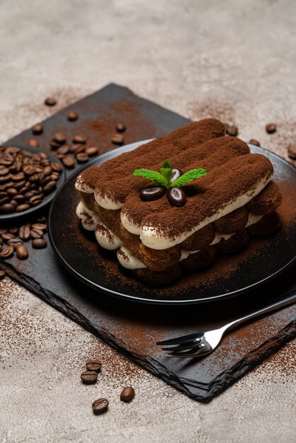 Dessert classico di tiramisù sul piatto ceramico su calcestruzzo