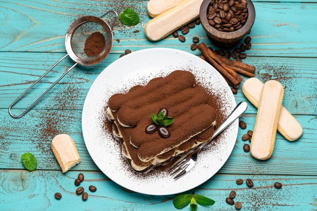 Dessert classico tiramisù su un piatto di ceramica su fondo di legno