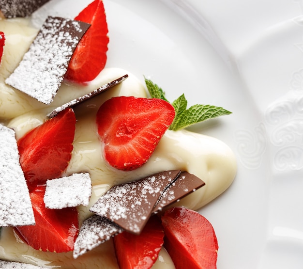 Dessert con fragole, crema alla vaniglia e cioccolato.