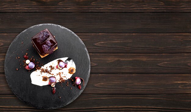 Dessert con noci in glassa di cioccolato a forma di cubo su ardesia nera