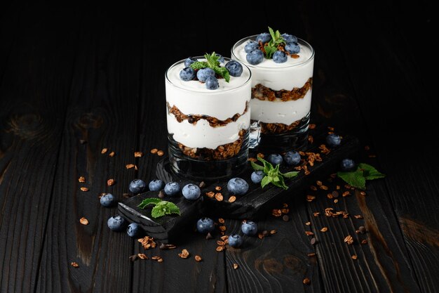 Dessert con ricotta mirtilli freschi e muesli in un bicchiere su fondo rustico