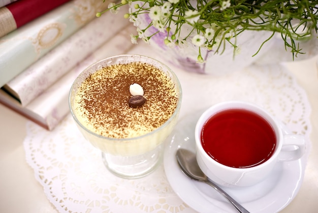 Dessert con tè sul tavolo con fiori e libri.