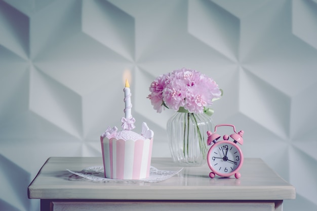 Dessert del bigné di compleanno e fiori rosa con la sveglia per la festa