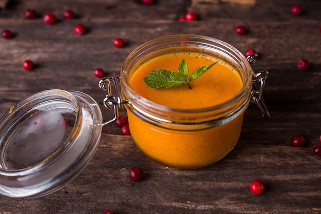 Dessert della mousse dell'olivello spinoso in un barattolo su una tavola di legno