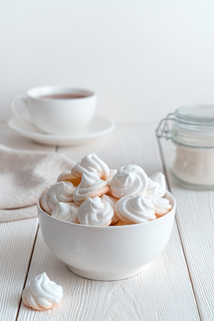 Dessert di meringa sullo sfondo di una tazza di tè, zucchero e tovaglioli. Vista verticale. Il concetto dei dolci.