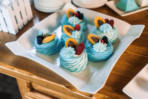 Dessert di meringa Torta Pavlova con frutti di bosco freschi su un piatto bianco Belle torte blu Clouseup