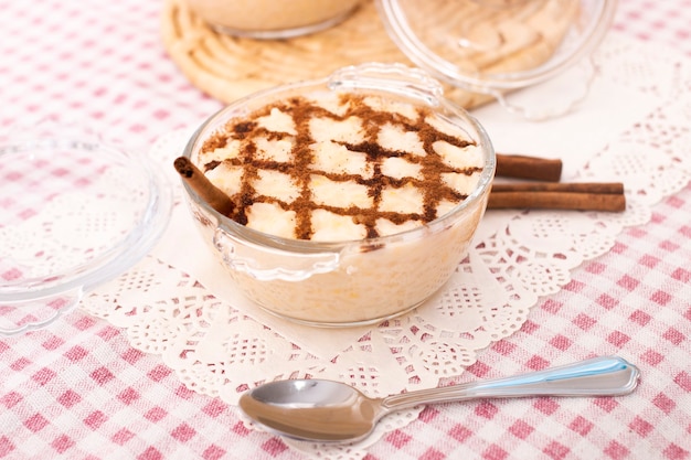 Dessert di riso dolce portoghese tradizionale su un tavolo con bastoncini di cannella.