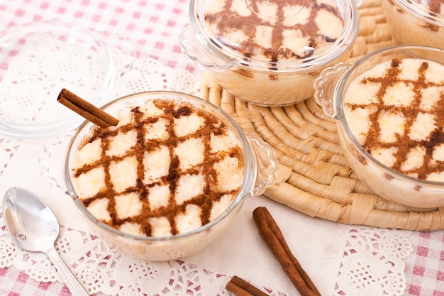 Dessert di riso dolce portoghese tradizionale su un tavolo con bastoncini di cannella.