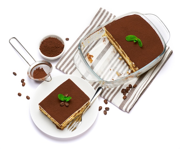 Dessert di tiramisù italiano tradizionale in teglia di vetro e porzione sulla piastra su bianco