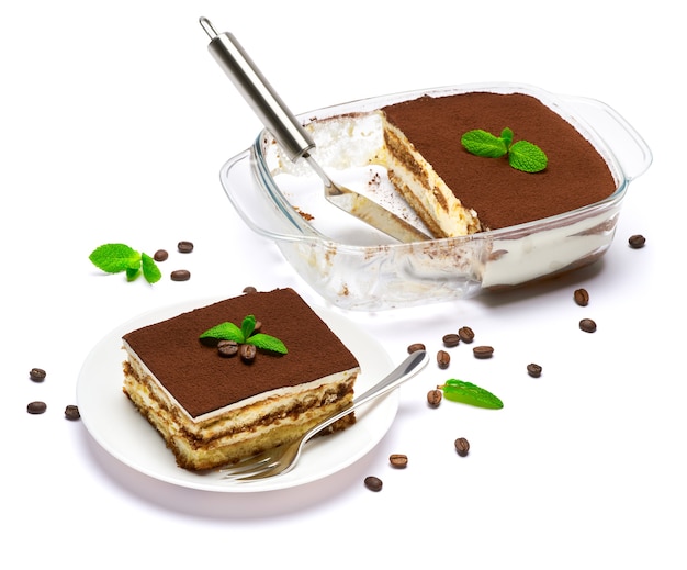 Dessert di tiramisù italiano tradizionale nella porzione di piatto di cottura di vetro sul piatto e sulla scapola isolata su bianco