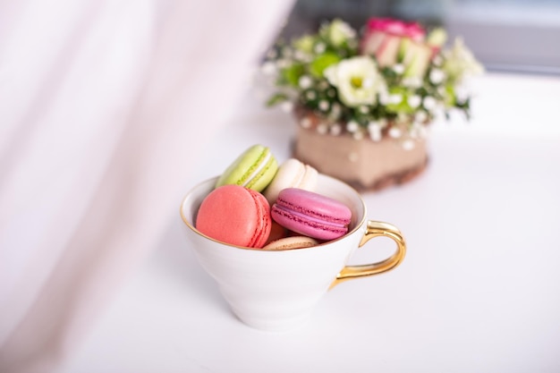 Dessert dolce, amaretti in tazza dorata e tulipani rosa sullo sfondo della finestra