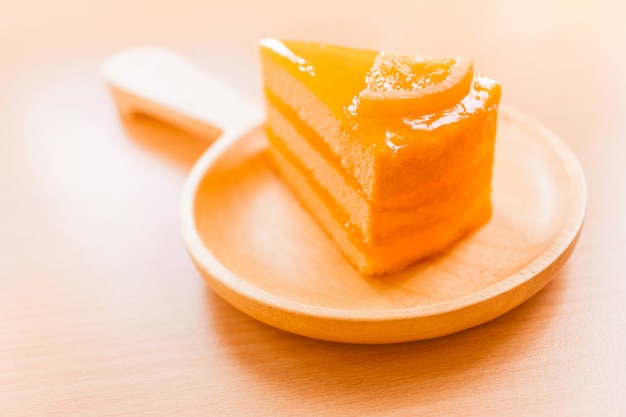 Dessert dolce del dolce arancio in piatto di legno sulla tavola di legno