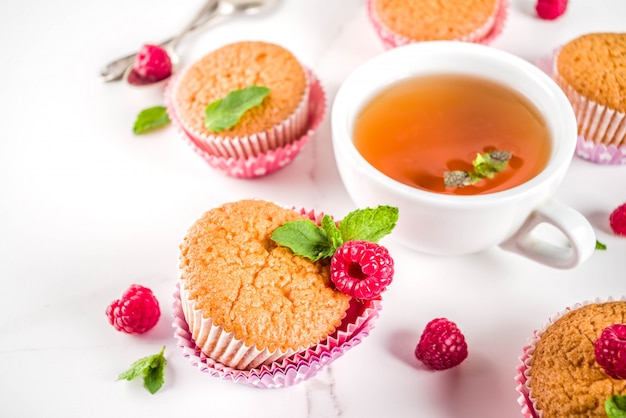 Dessert dolce, muffin al forno fatto in casa con marmellata di lamponi, servito con tè, lamponi freschi e menta