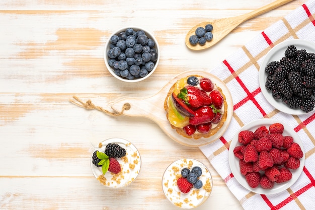 Dessert dolci con frutti di bosco freschi su una superficie di legno