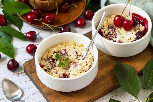 Dessert estivo fatto in casa Crumble di ciliegie in una teglia su un ripiano in legno