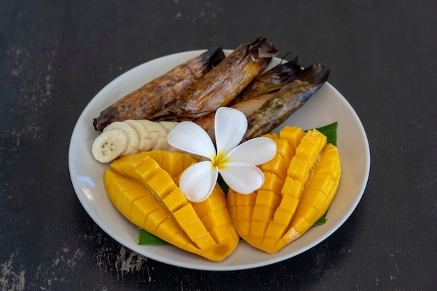 Dessert in stile tailandese mango giallo con banana riso appiccicoso in foglie di palma Mango giallo e riso appiccicoso è cibo tradizionale popolare della Thailandia Primo piano