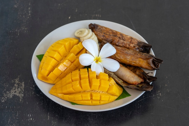 Dessert in stile tailandese, mango giallo con riso appiccicoso alla banana in foglie di palma. Il mango giallo e il riso appiccicoso sono il cibo tradizionale popolare della Thailandia. Avvicinamento