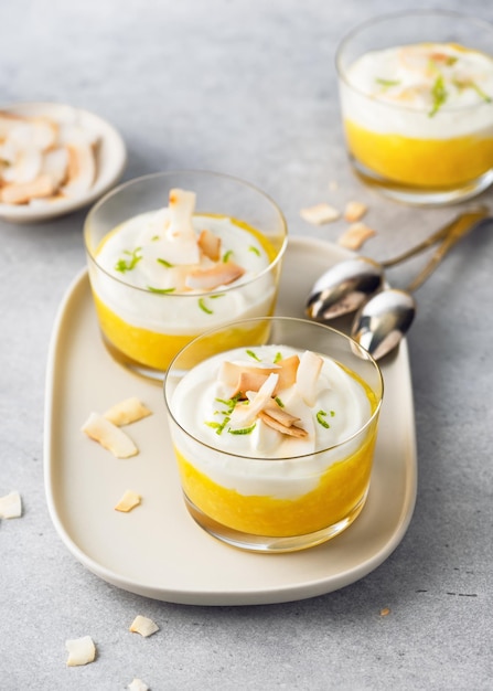 Dessert sano alla crema di frutta tropicale con strati bianchi e arancioni di purea di mango e crema di formaggio