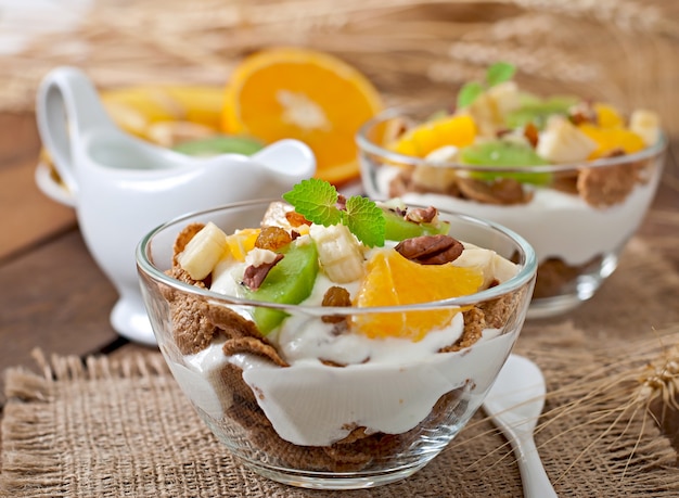 Dessert sano con muesli e frutta in una ciotola di vetro sul tavolo