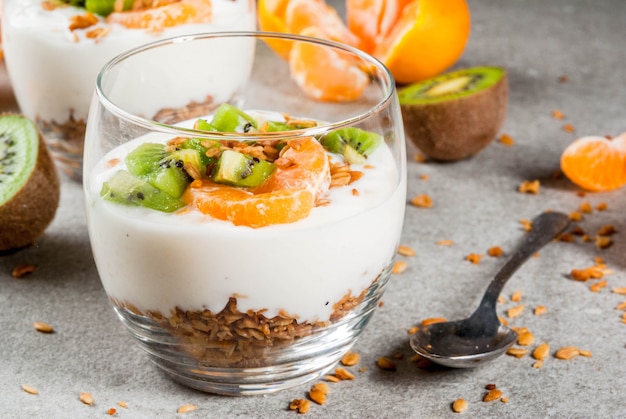 Dessert sano di muesli allo yogurt di mandarino e kiwi a colazione, con ingredienti, tavolo in pietra grigia, dessert di muesli allo yogurt di rine e kiwi