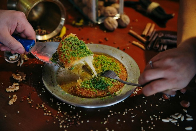 Dessert turco kunefe, kunafa, kadayif con polvere di pistacchio e formaggio caldo mangiato un dolce