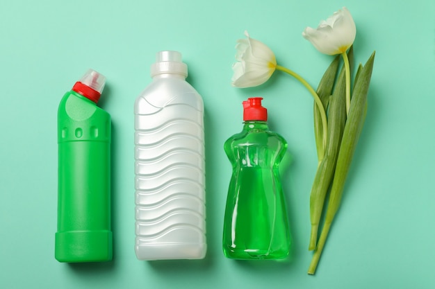 Detergenti vuoti e tulipani su sfondo di menta, spazio per il testo