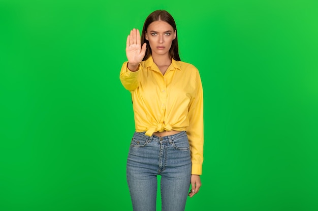 Determinata donna che gesturing smettere di guardare la fotocamera su sfondo verde