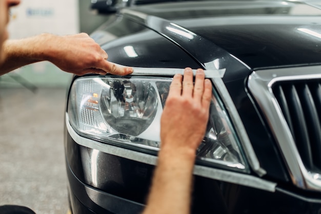 Dettagli automatici dei fari delle auto sul servizio di autolavaggio. Il lavoratore prepara il vetro per la lucidatura