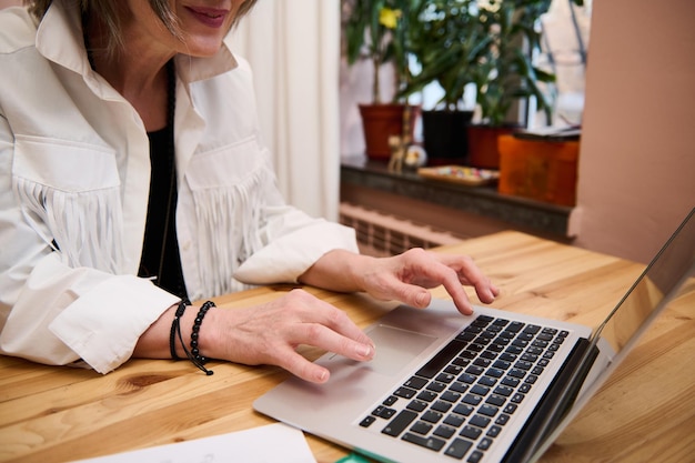 Dettagli delle mani di un piccolo imprenditore stilista di moda che lavora al computer portatile sul posto di lavoro