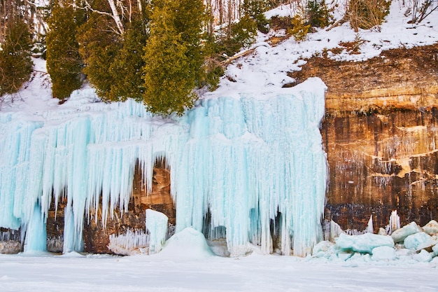 Dettagli di scogliere rocciose in inverno coperti da formazioni di ghiaccio blu e ghiaccioli