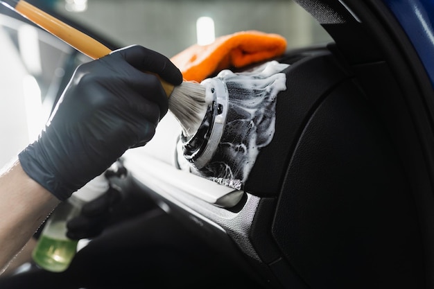 Dettagli interni dell'auto Sistema di pulizia dell'aria con schiuma e detergente mediante spazzola Il lavoratore nel servizio di pulizia automatica pulisce l'auto all'interno