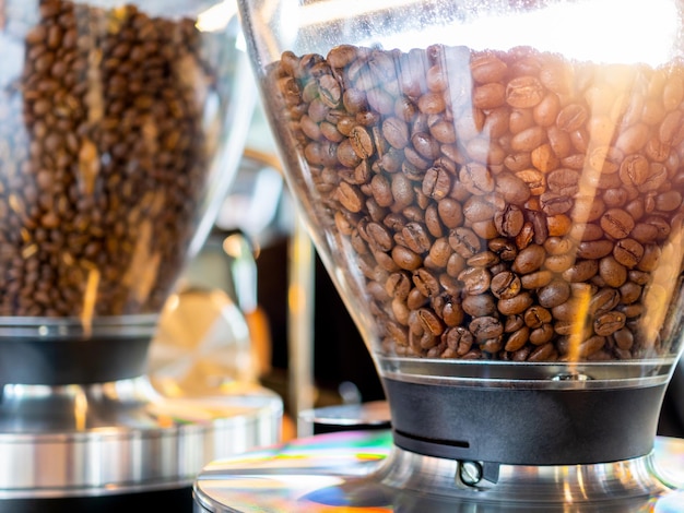 Dettagli strutturati del primo piano dei chicchi di caffè in una macchina che si prepara per la miscela nella caffetteria o sullo sfondo del caffè con la luce del sole al mattino