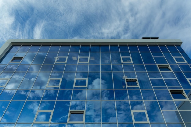 Dettaglio architettonico della facciata con molteplici riflessi del cielo nuvoloso e del sole Esterno di un edificio moderno Architettura sfondo astratto