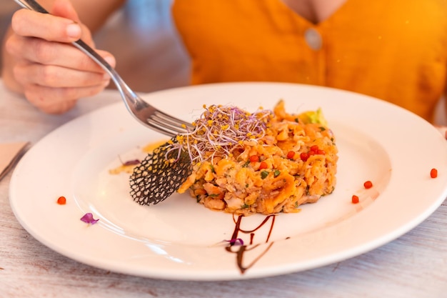 Dettaglio con una mano femminile che cena in un ristorante sulla spiaggia in vacanza al tramonto mangiando pesce