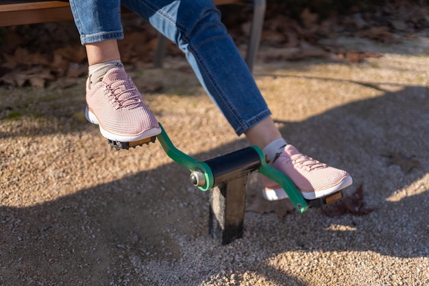 Dettaglio dei piedi delle donne che pedalano su un attrezzo ginnico in un parco pubblico