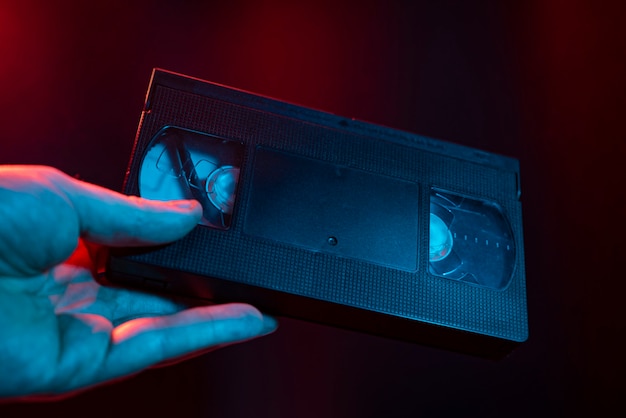Dettaglio della cassetta VHS preso in mano in una luce buia