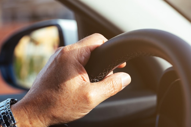 Dettaglio della mano di un uomo sul volante di un'auto