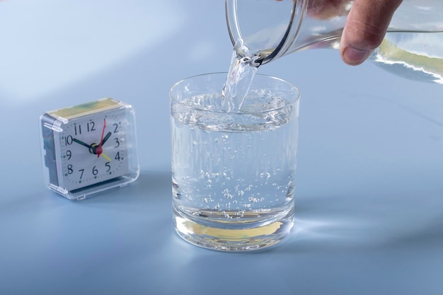 Dettaglio della persona che riempie il bicchiere del concetto di idratazione dell'acqua
