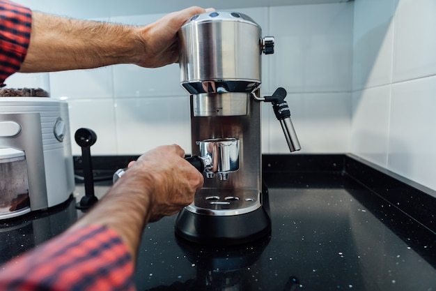 Dettaglio delle mani dell'uomo che preparano un espresso