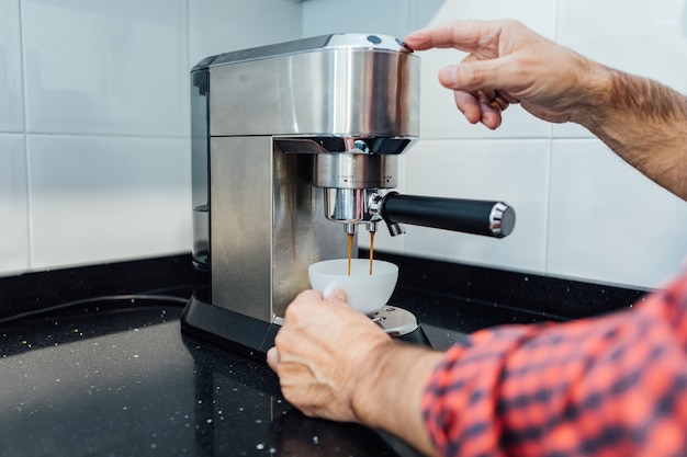 Dettaglio delle mani dell'uomo che preparano un espresso