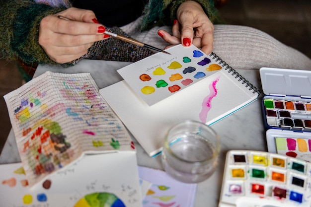 Dettaglio delle mani delle donne con carte e tabella dei colori per la pittura