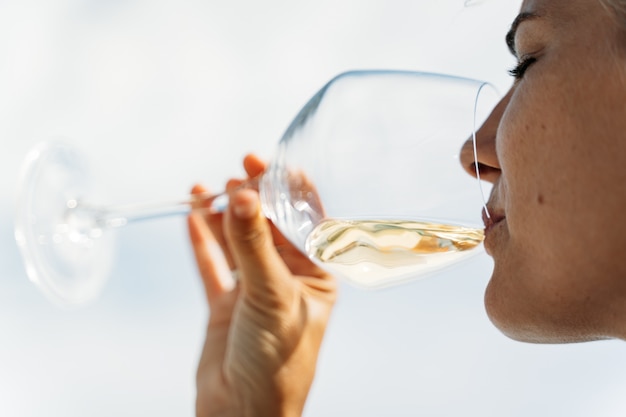 Dettaglio di una donna che beve vino bianco all'aperto