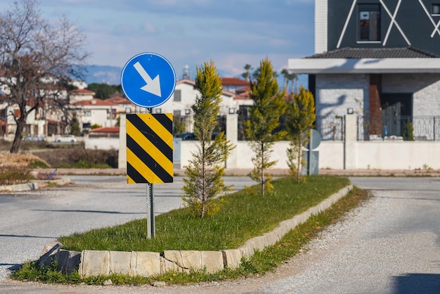 Deviazione del segnale stradale del primo piano sulla destra contro lo sfondo della strada