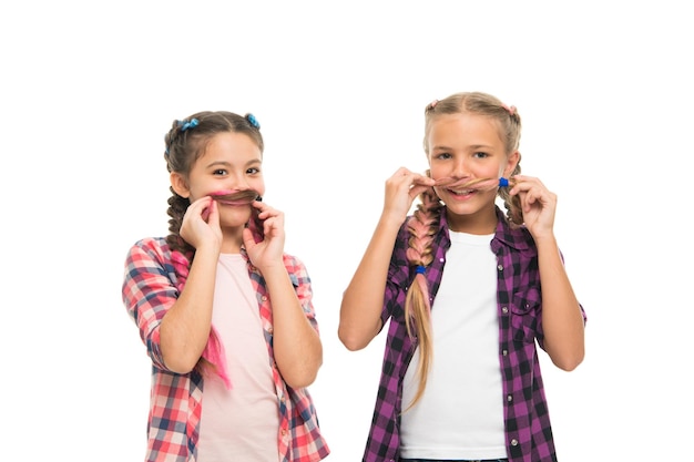 Di chi è meglio i baffi. Le bambine indossano acconciature intrecciate. Le ragazze felici si divertono con i capelli. Le ragazze carine sorridono con uno sguardo divertente. Piccole ragazze in stile casual isolate su bianco. Moda e bellezza.