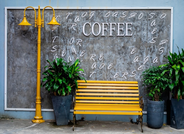 Di colore giallo brillante da banco e lampione e vasi di fiori con piante contro un muro di cemento grigio su una strada a da Nang, Vietnam, close-up