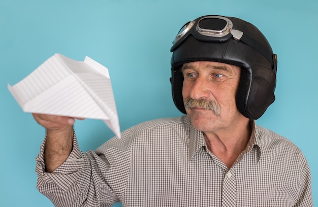 Di età compresa tra uomo divertente come un pilota con cappello e occhiali utilizzando l&#39;aereo di carta