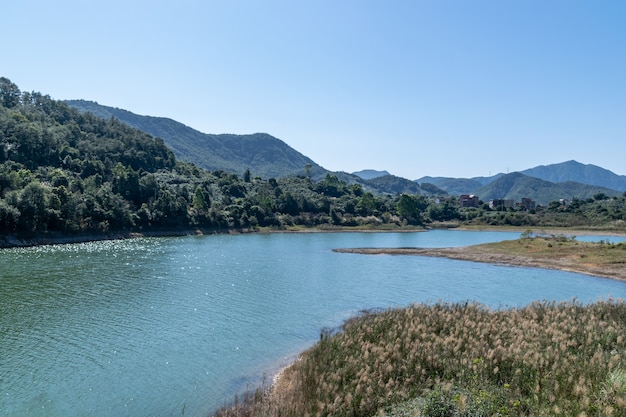 Di fronte al lago c'è la montagna, il cielo è blu e l'acqua del lago è blu